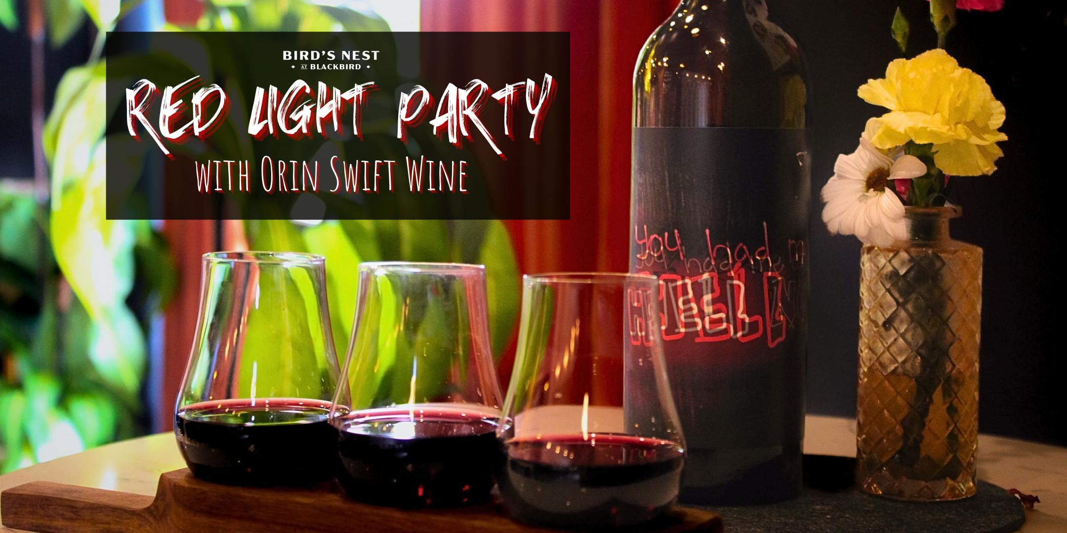 Banner reading 'Red Light Party' at Blackbird over a wine setup with a bottle, flowers in a vase, and three glasses of red wine on a table